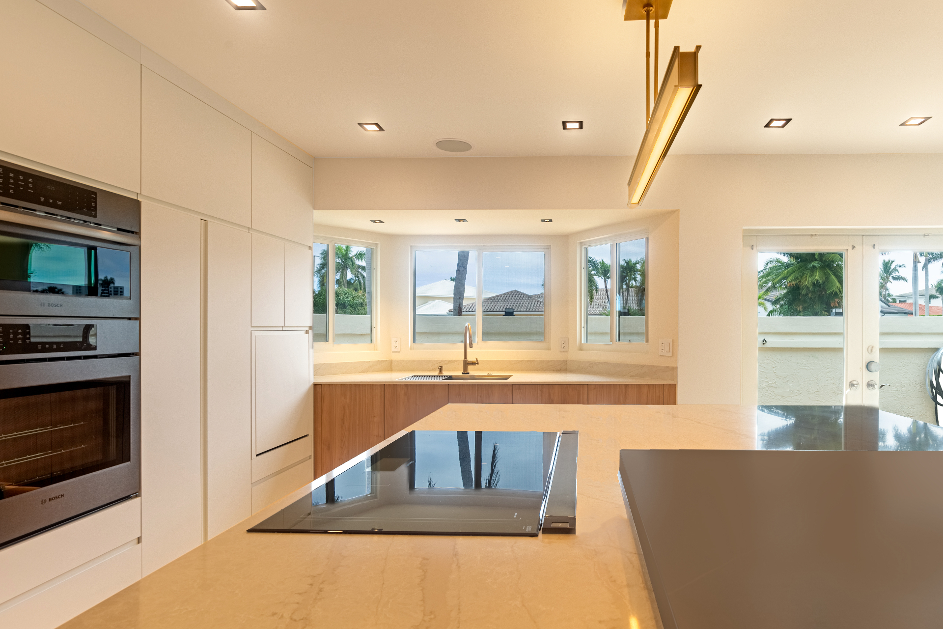 Kitchen with cooktop island and bay window overlooking palms